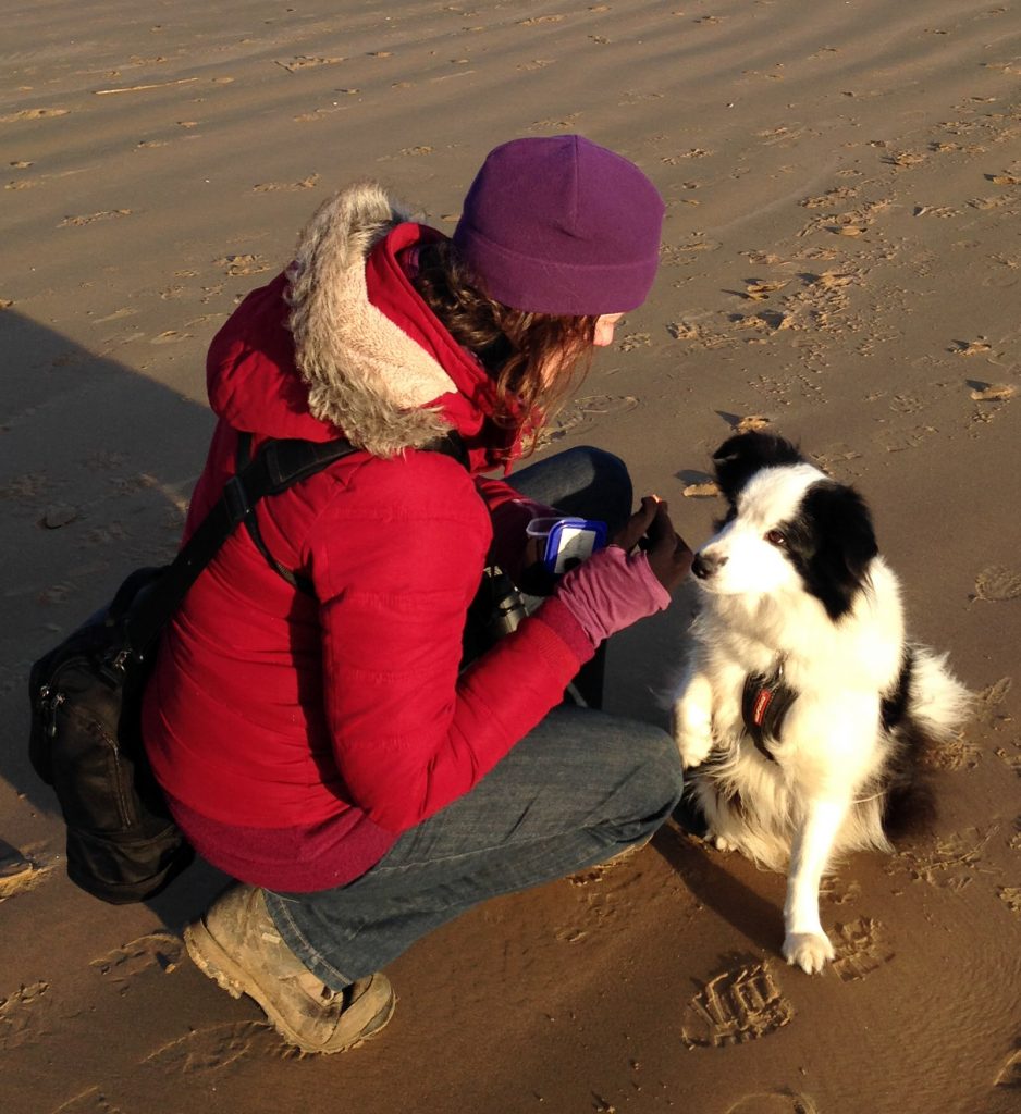 Photo of Ruth with her dog Amy on the beach.